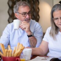 介護保険料の負担が重く、家計の計算をする高齢者と家族の様子。